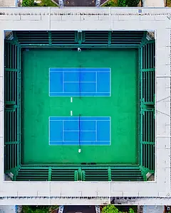 Aerial view of a tennis arena with two blue courts